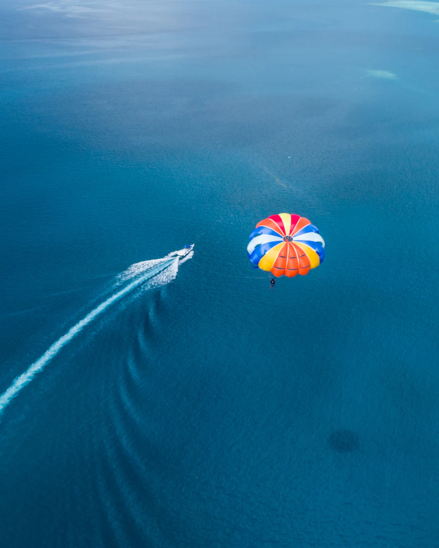 A speedboat towing a parasail across bright blue water
