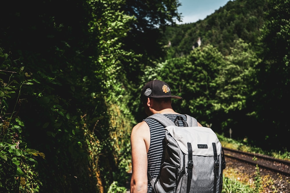 shallow focus photo of man wearing black flat brim cap and gray backpack