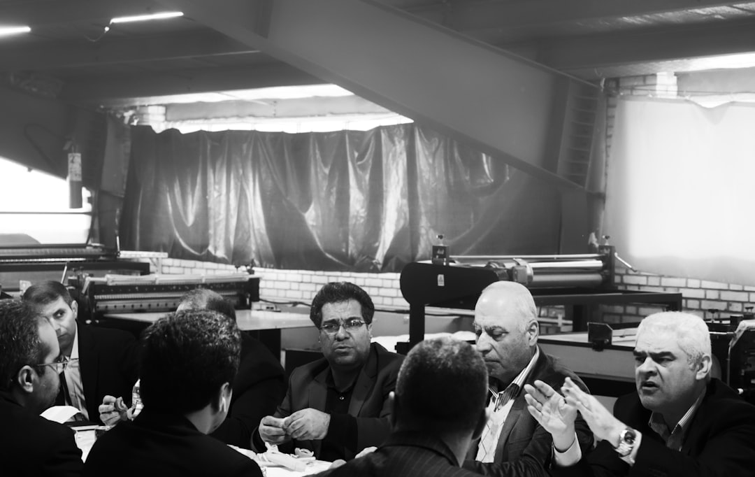 grayscale photography of group of person sitting indoors