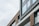 A modern building facade with large glass windows and stylish horizontal wooden slats. The architecture features clean lines and a minimalist design, highlighted by a combination of gray and neutral tones.