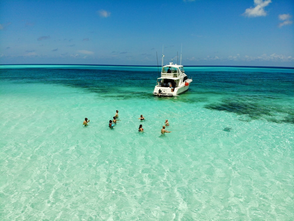 people on body of water across white yacht