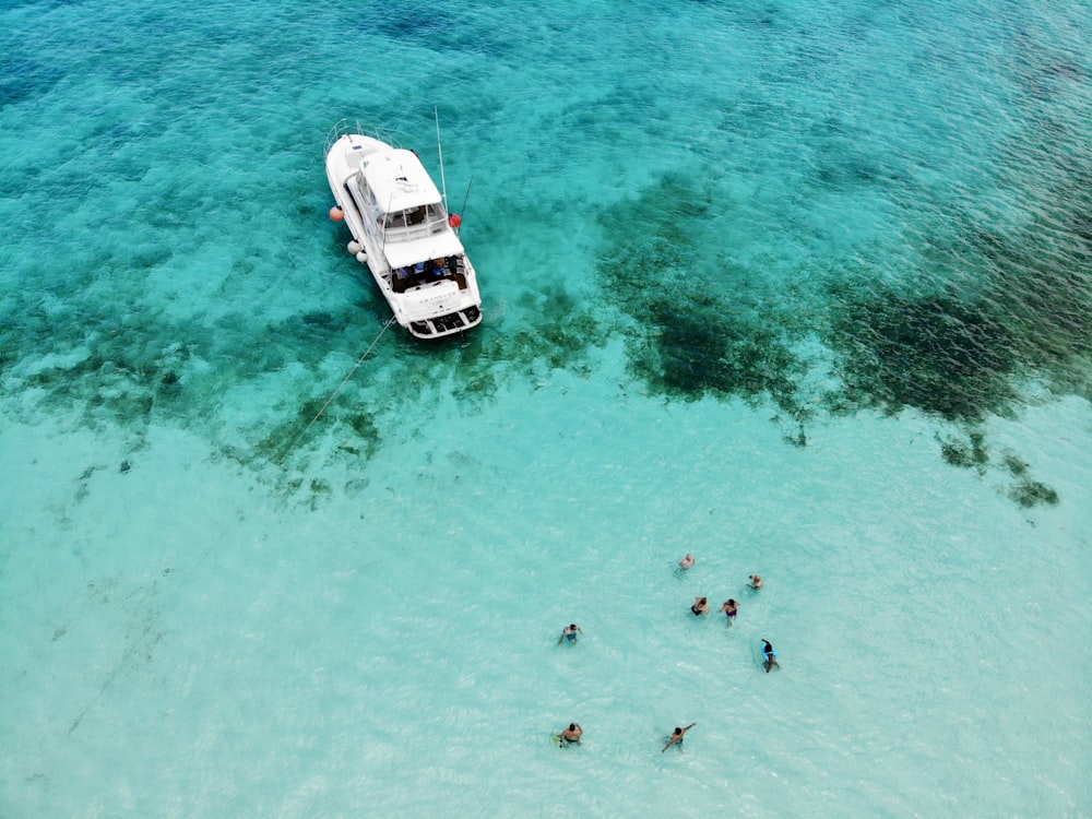 Photographie à vol d’oiseau de personnes près d’un bateau blanc