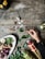 A rustic wooden table with assorted hot sauces and fresh ingredients for cooking.