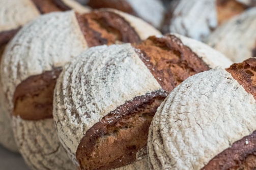 Several round loaves of rustic bread with a crusty, flour-dusted surface. The bread features deep scoring patterns and an artisanal appearance.