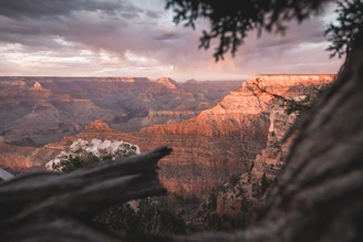 A breathtaking view of the Yellowstone Grand Canyon rim at sunrise, with vibrant colors illuminating the rugged cliffs and winding river below.