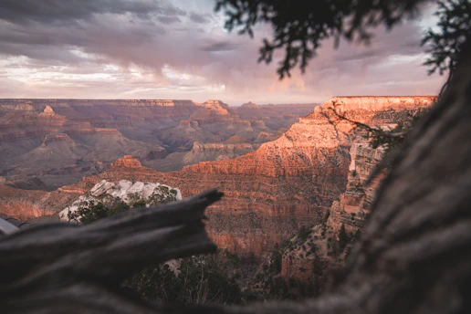 A breathtaking view of the Yellowstone Grand Canyon rim at sunrise, with vibrant colors illuminating the rugged cliffs and winding river below.