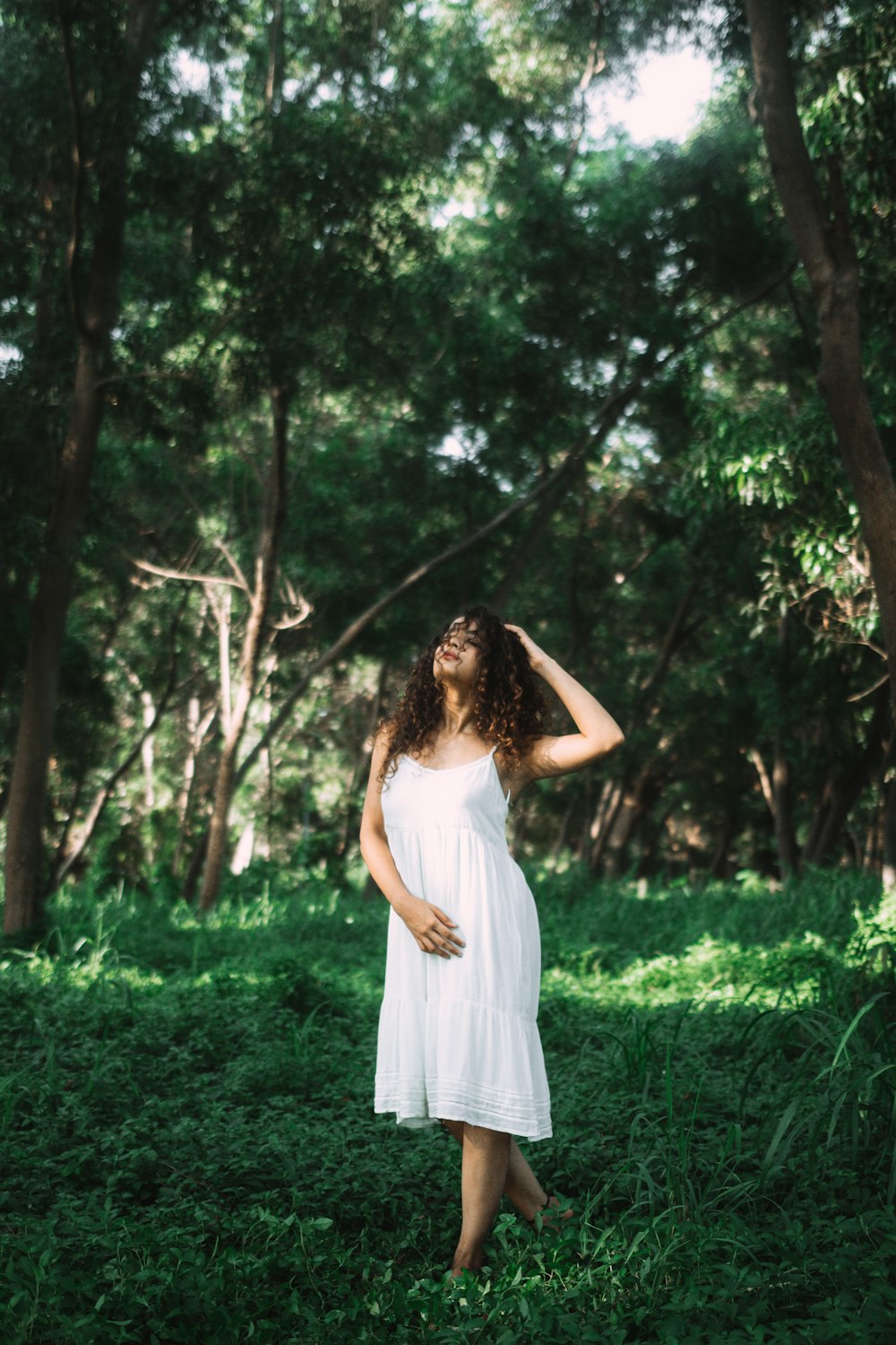 woman in white cami dress walking in woods