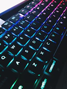 Close-up of hands typing on a modern keyboard with floating blue gradient elements.