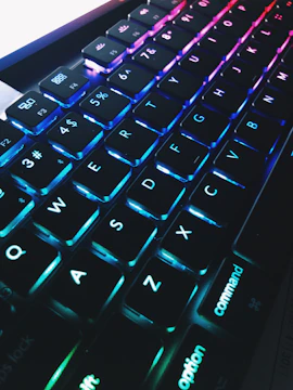 Close-up of hands typing on a modern keyboard with floating blue gradient elements.