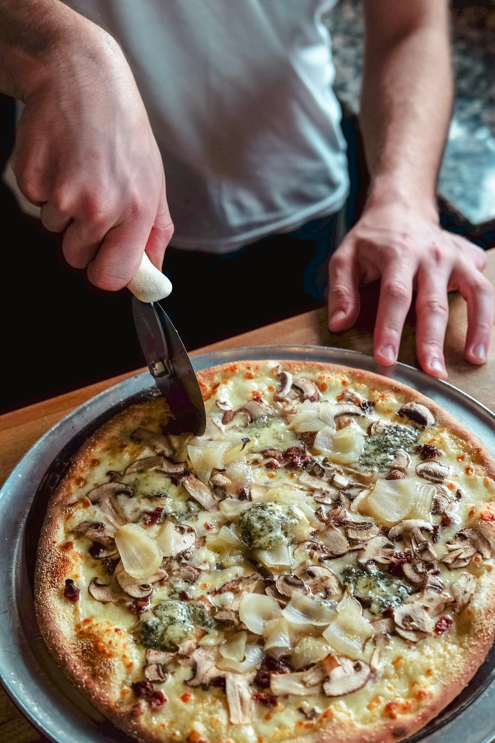 person standing and about to slice pizza