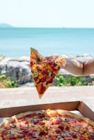 A happy customer holding a slice of pizza with a city view in the background.