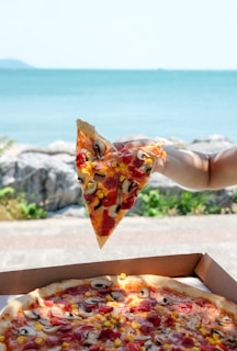 A happy customer holding a slice of pizza with a city view in the background.