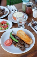 bread with meat, sliced tomato, and green chili on plate