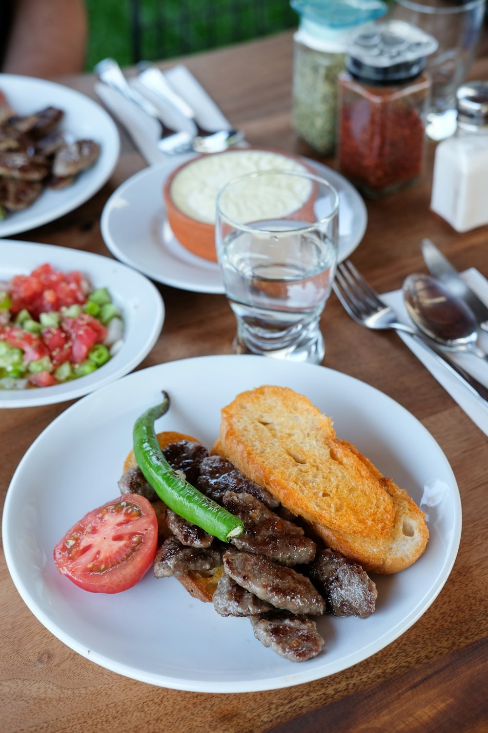 bread with meat, sliced tomato, and green chili on plate