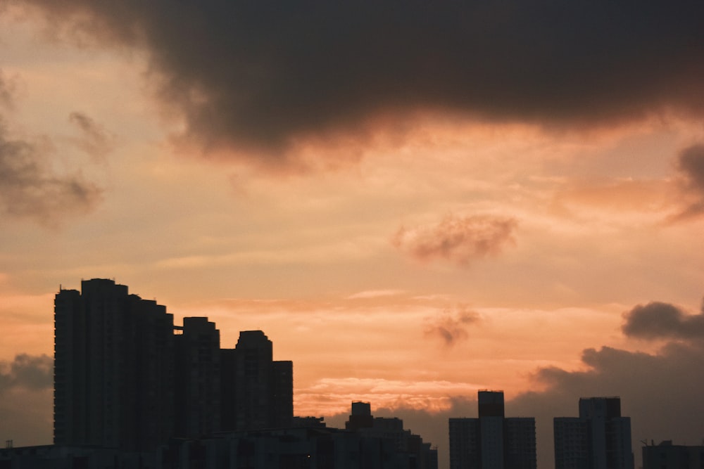 orange and grey sky over silhouette of buildings at dusk