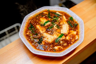 Close-up of silky mapo tofu served in a traditional ceramic bowl.