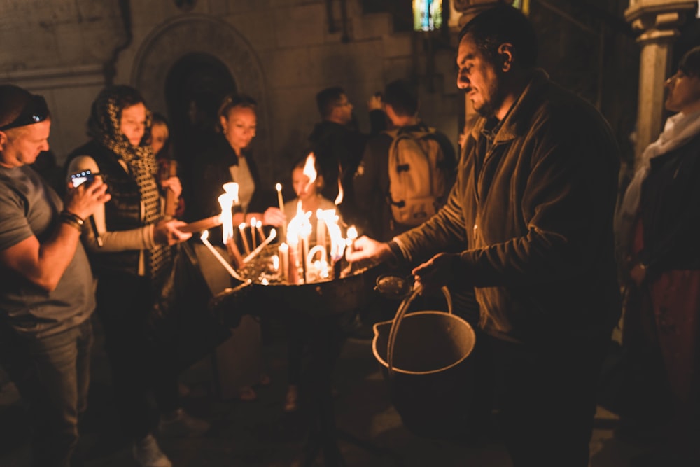 group of people standing around table with lighted candles