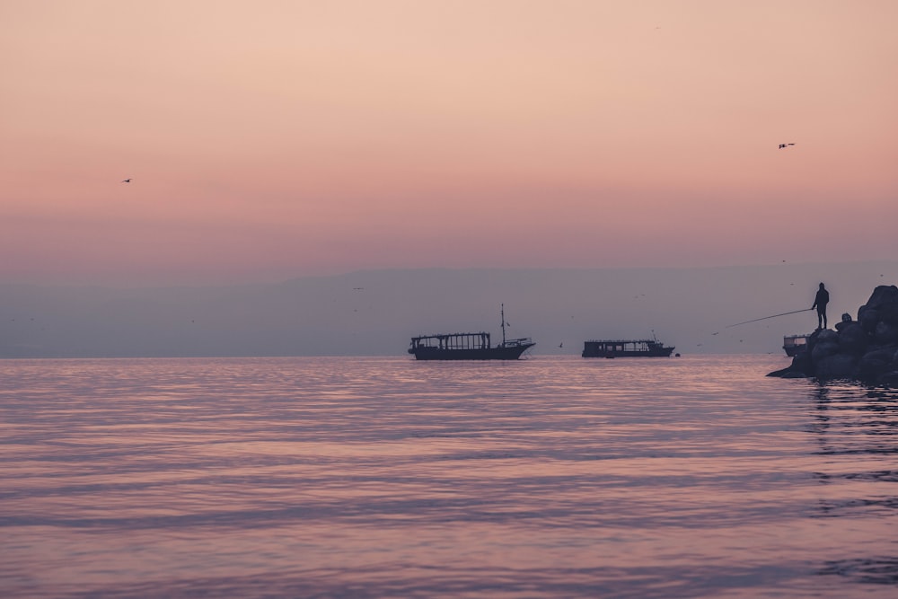 homme pêchant près de deux bateaux