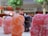 Close-up view of colorful, sugar-coated gummy candies shaped like small bears, with blurred trees and a mall interior in the background.