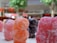 Close-up view of colorful, sugar-coated gummy candies shaped like small bears, with blurred trees and a mall interior in the background.