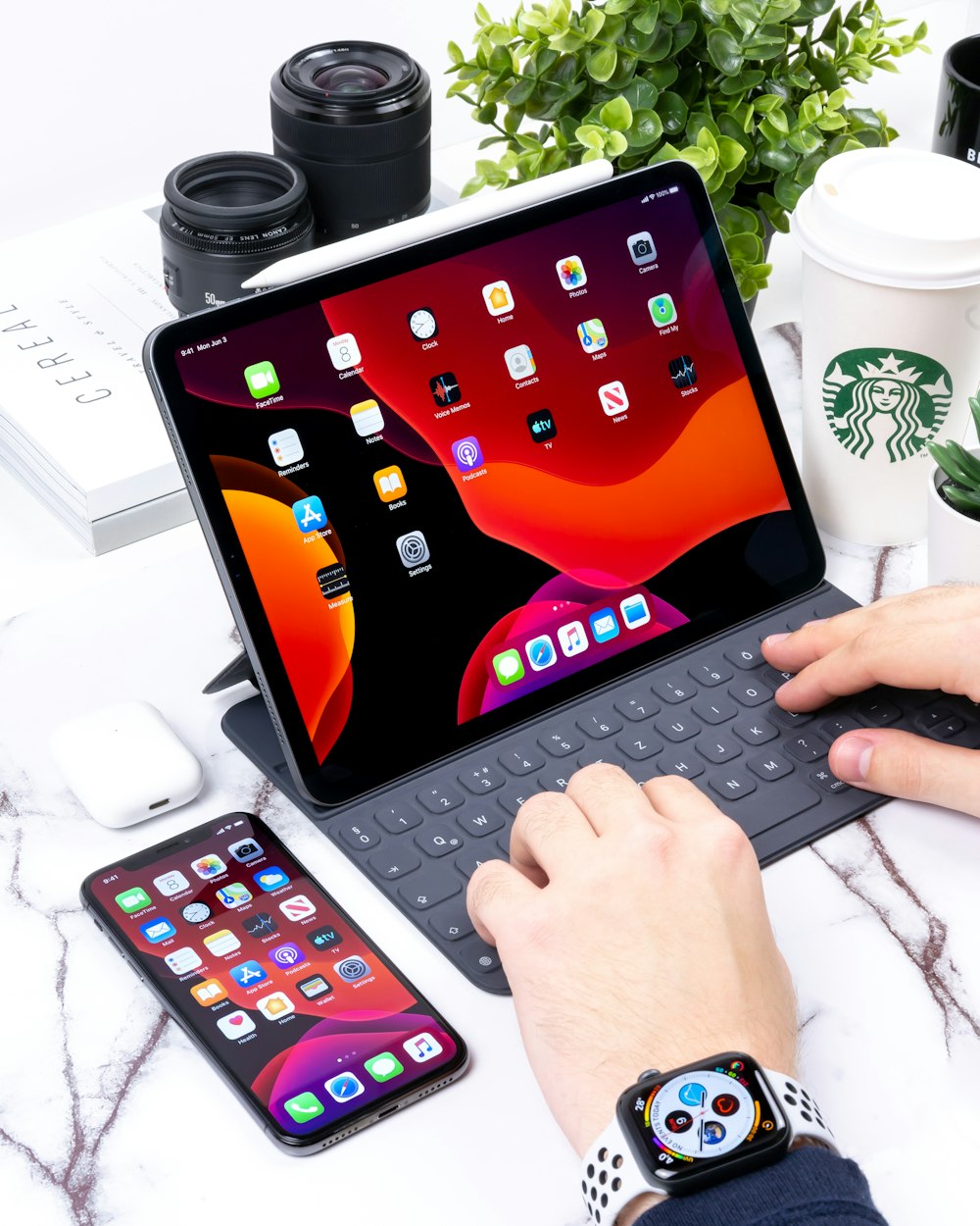黒のApple iPad用の灰色のBluetoothキーボードで入力する人