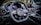 A luxury car interior featuring a sleek design with a focus on the steering wheel. The dashboard includes modern digital displays and metallic accents, enhancing the overall elegance and sophistication. The ambient lighting and polished surfaces reflect a high level of craftsmanship.