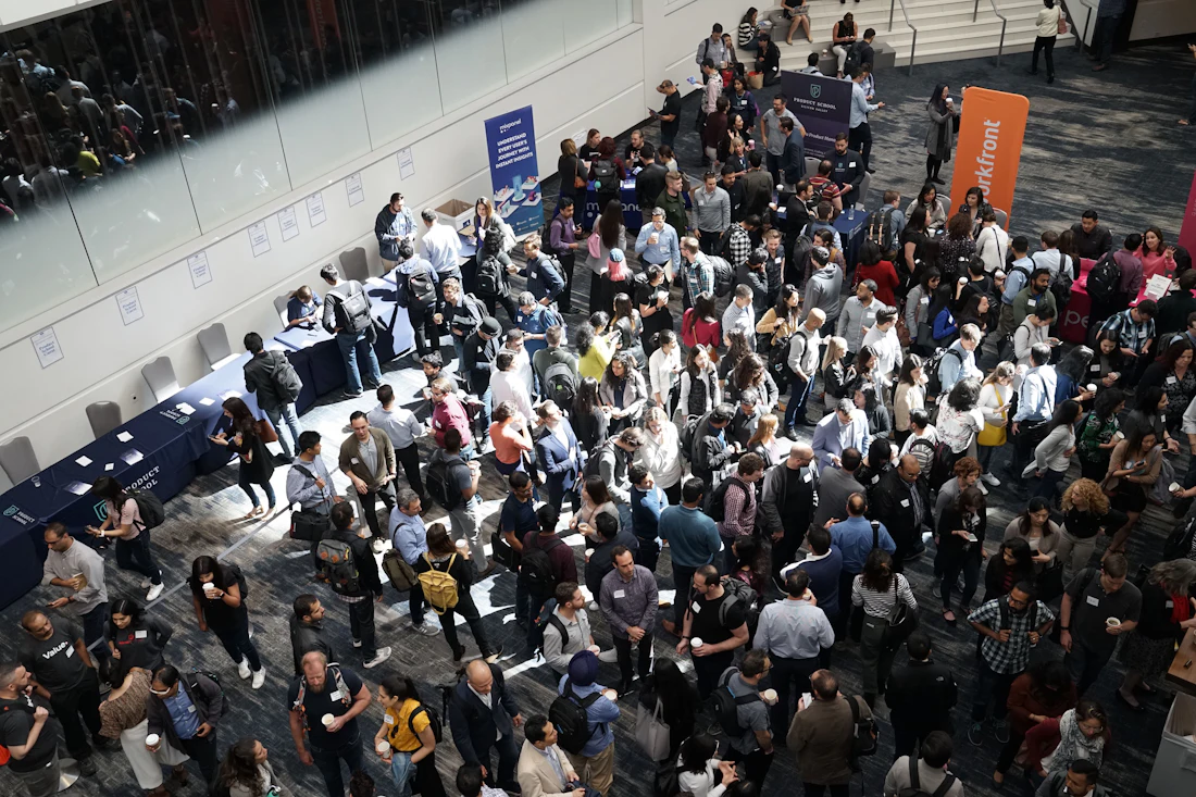 Attendees crowding the concourse between exhibitor stands at a trade show, seen from above
