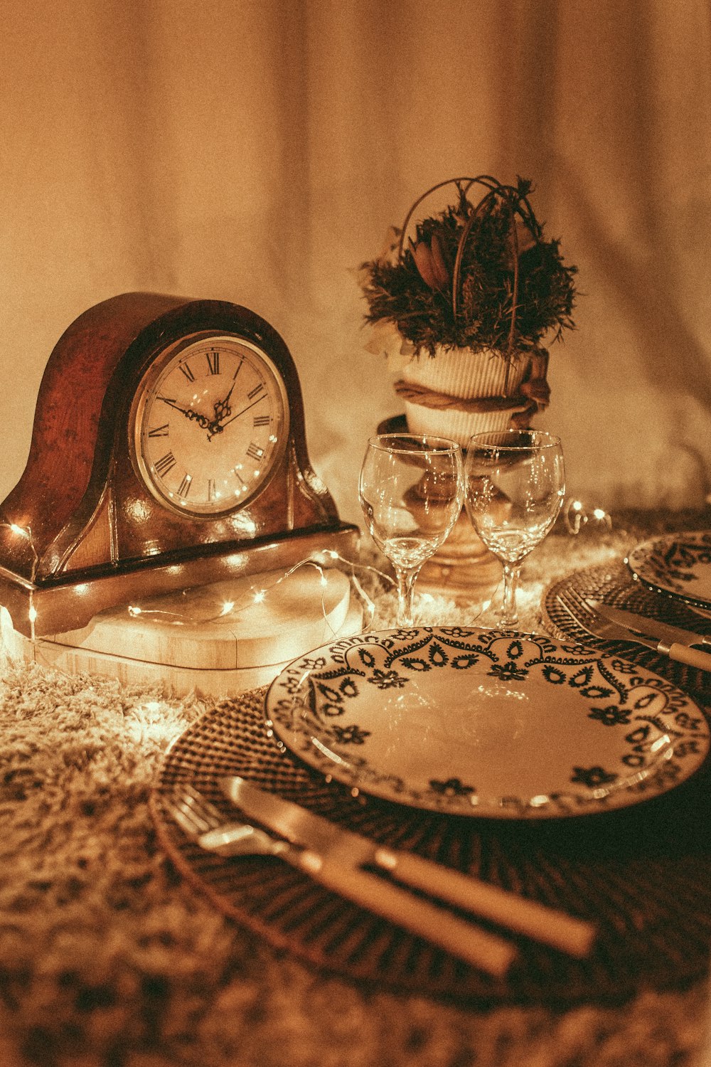 empty white plate near wine glasses and anniversary clock displaying 1:50