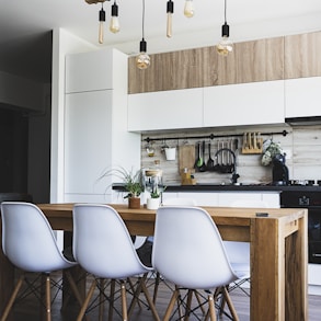 brown wooden dining table with white chairs near kitchen