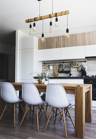 brown wooden dining table with white chairs near kitchen