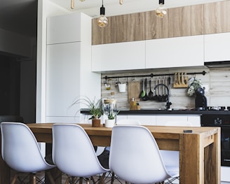 brown wooden dining table with white chairs near kitchen