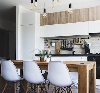 brown wooden dining table with white chairs near kitchen