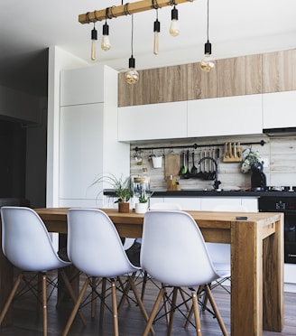 brown wooden dining table with white chairs near kitchen