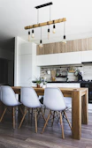 brown wooden dining table with white chairs near kitchen