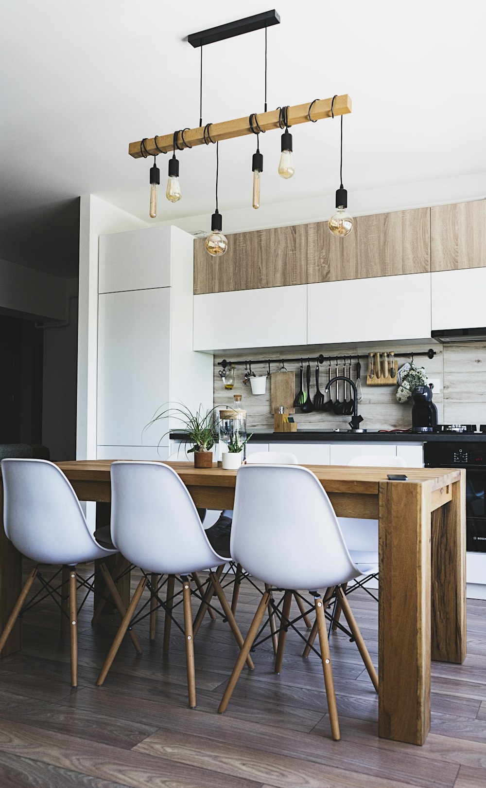 Table à manger en bois marron avec des chaises blanches près de la cuisine