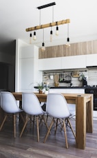 brown wooden dining table with white chairs near kitchen