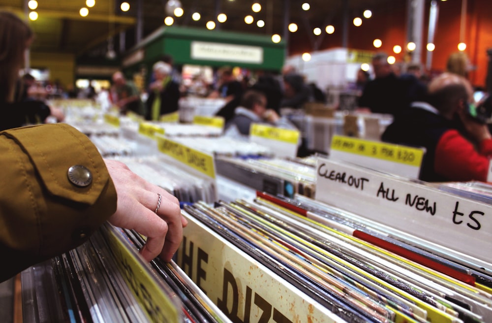 person in brown jacket selecting vinyl sleeves