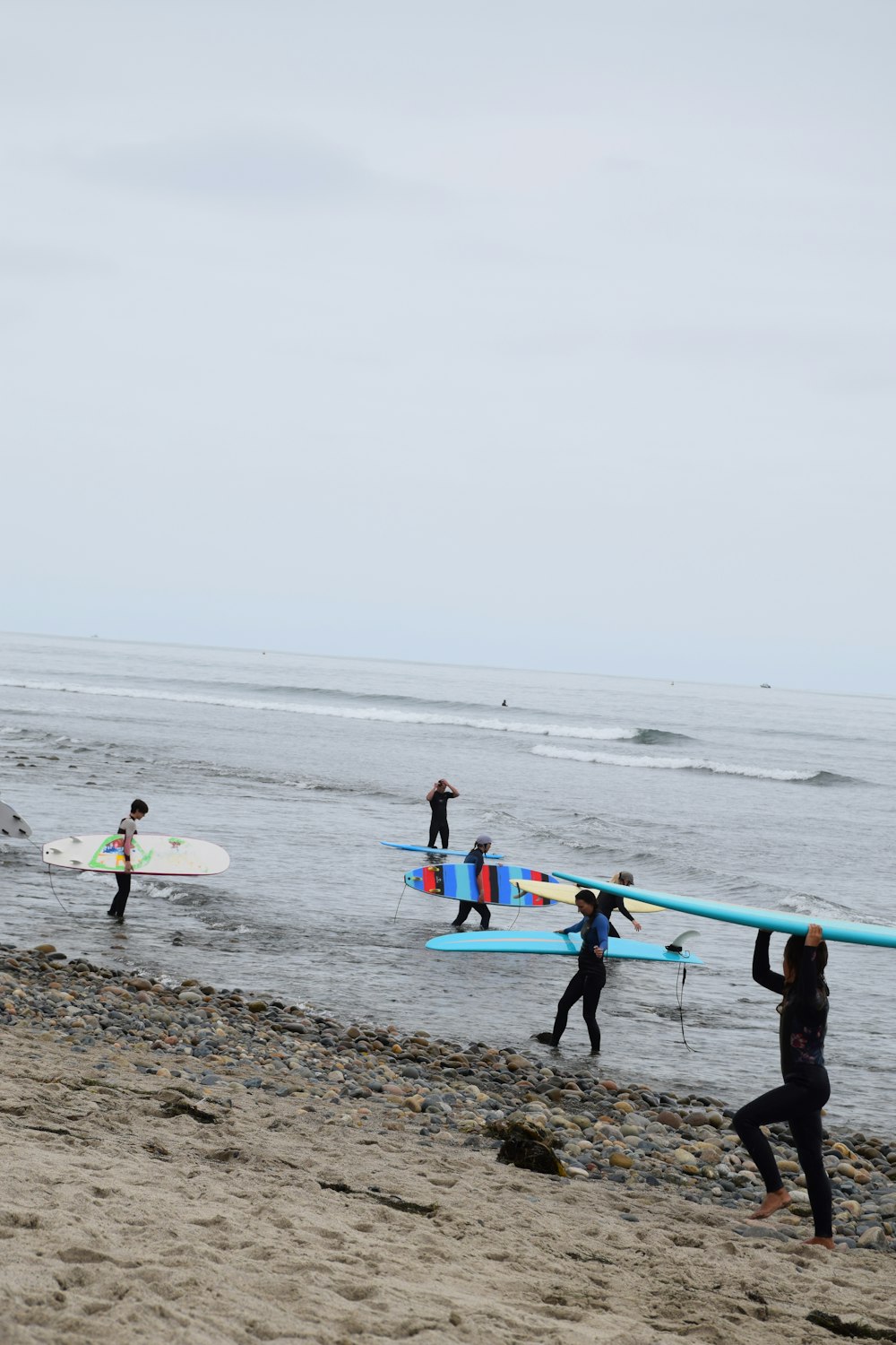 person carrying blue surfboard on beach