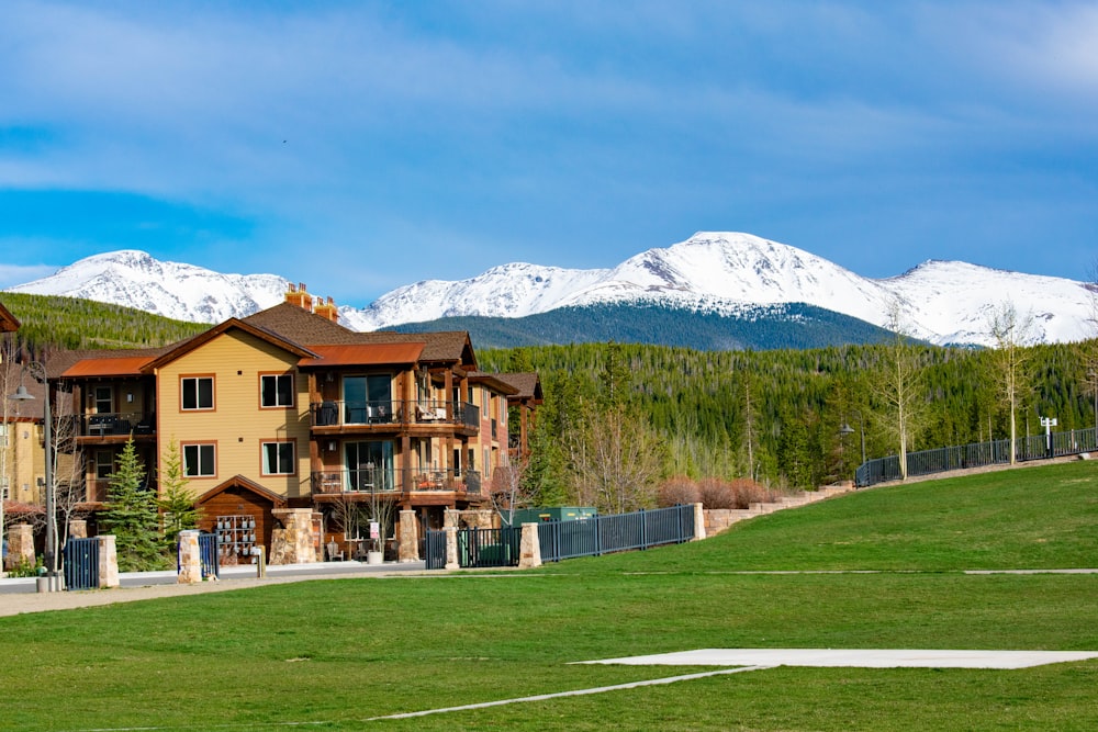 brown house near grass field with view of snow mountain during daytime
