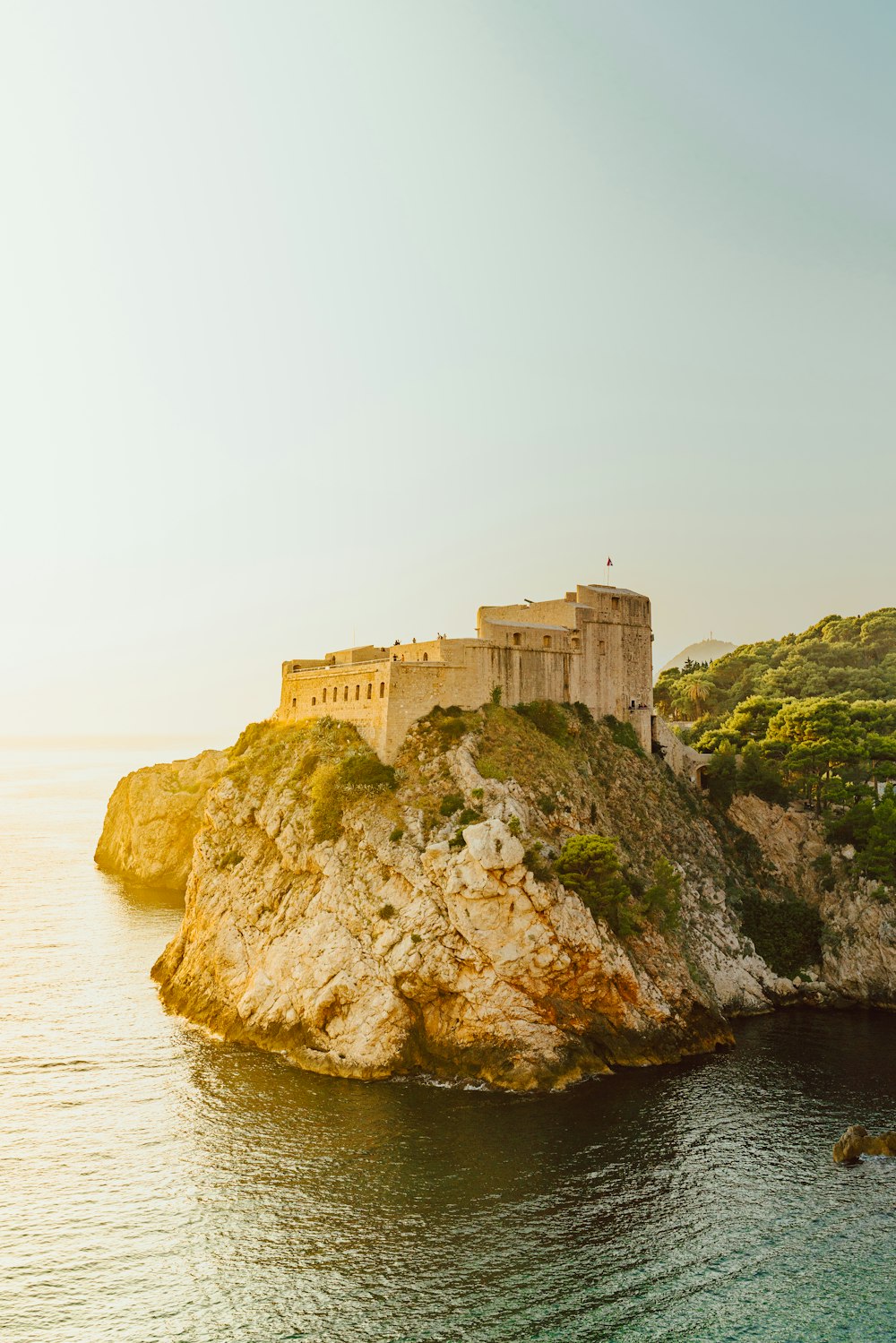 beige castle on rock cliff beside body of water