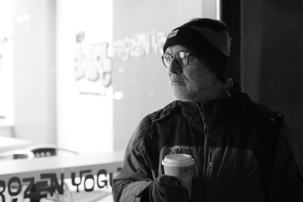 man holding a cup grey-scale photography