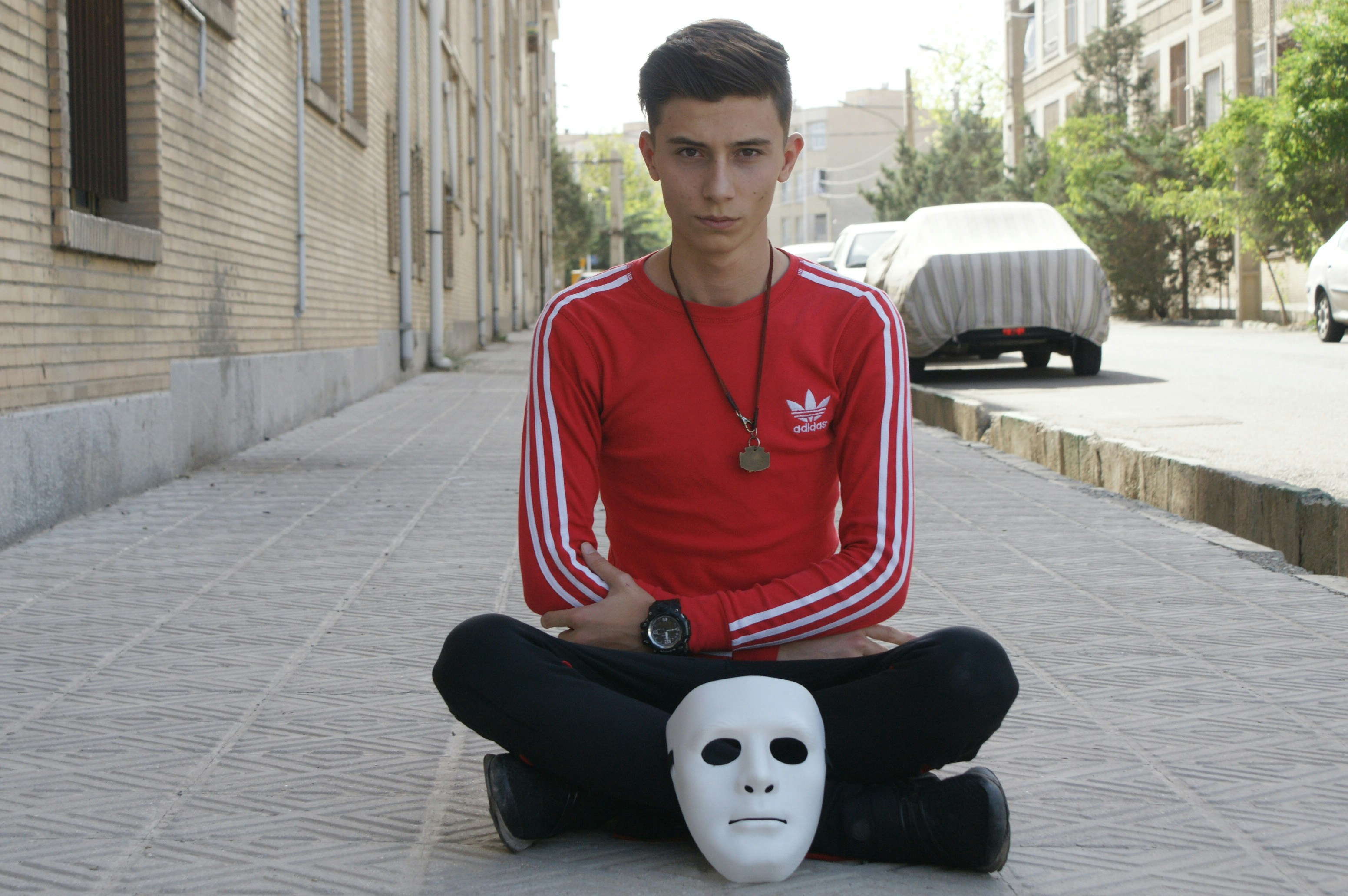 man sitting on pavement with mask