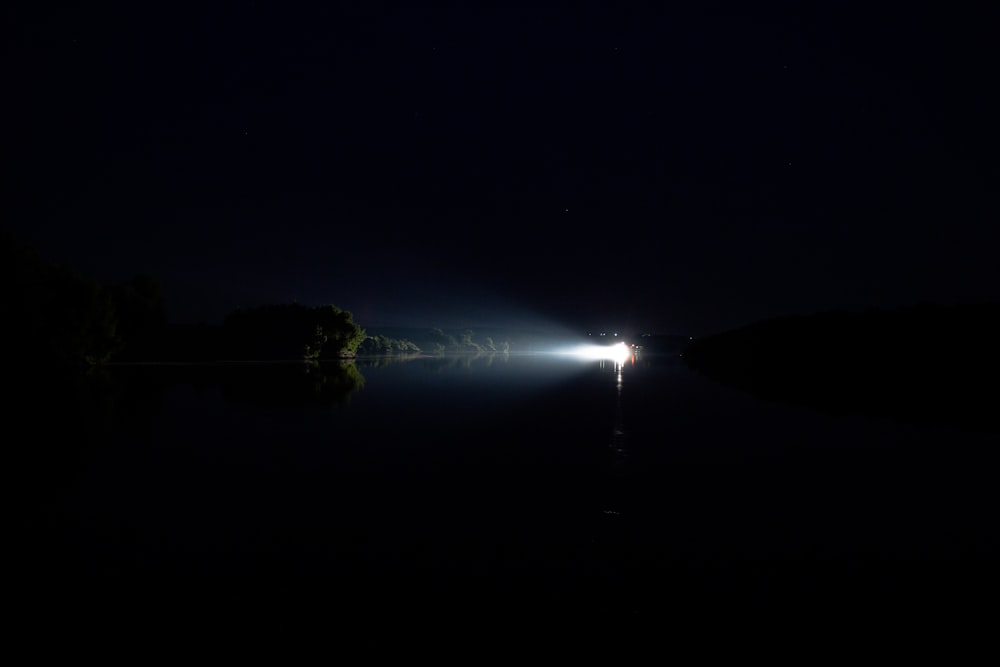 a light shines in the dark over a body of water