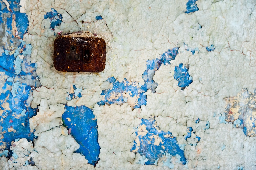 a rusted metal object sitting on top of a blue and white wall