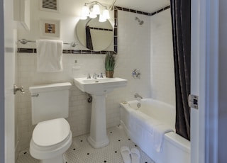 white ceramic toilet bowl beside pedestal sink