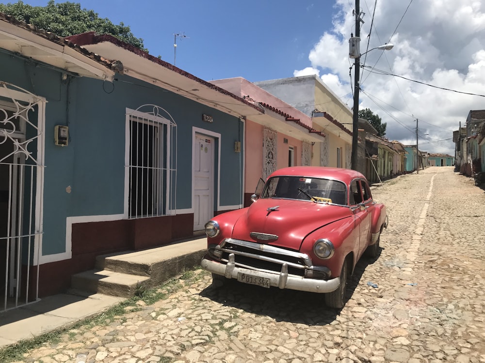 red vehicle parked beside blue house