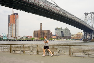 woman running under bridge during daytime