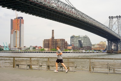 woman running under bridge during daytime