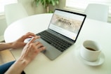 black and gray laptop beside teacup