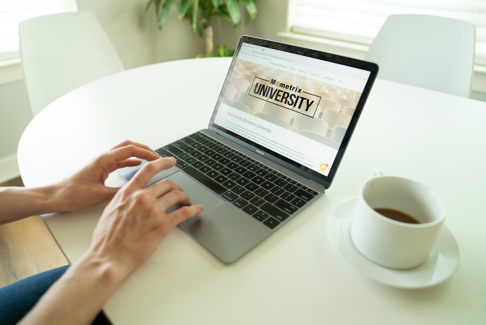 black and gray laptop beside teacup